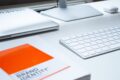 Office Desk Setup mit Screen, Laptop, Tastatur und Brand Identity Buch © Unsplash, Patrik Michalicka